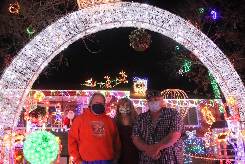 From left, Ron Kloewer, Melanie Kloewer and family friend Mike Rasmussen, in front of the Kloewer home on South Elati Street in Englewood. The family is known for their elaborate and whimsical Christmas decorations.